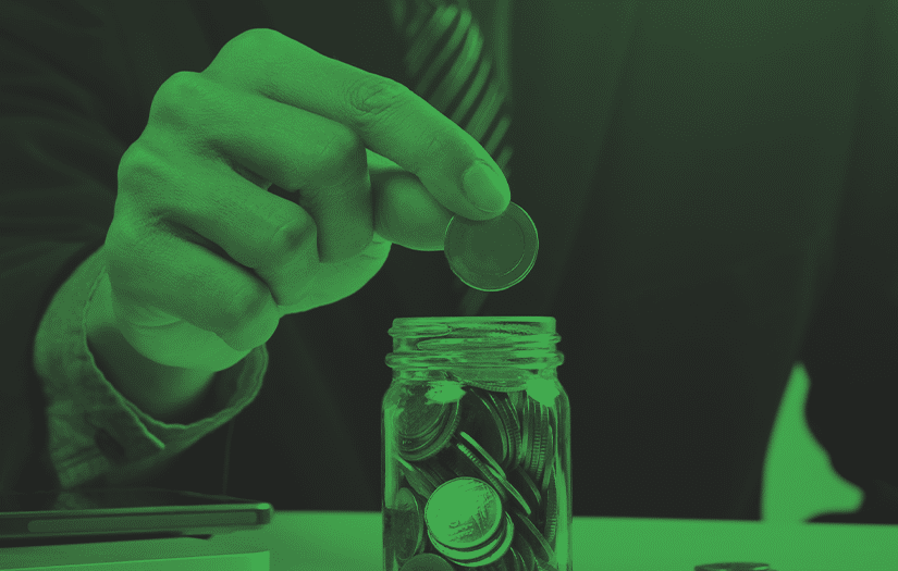 Um executivo colocando moedas em um pote de vidro