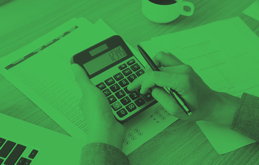 Uma mesa com vários documentos e um homem fazendo contas na calculadora